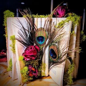 Crystalized vintage leather bound book with peacock feathers, flowers and moss